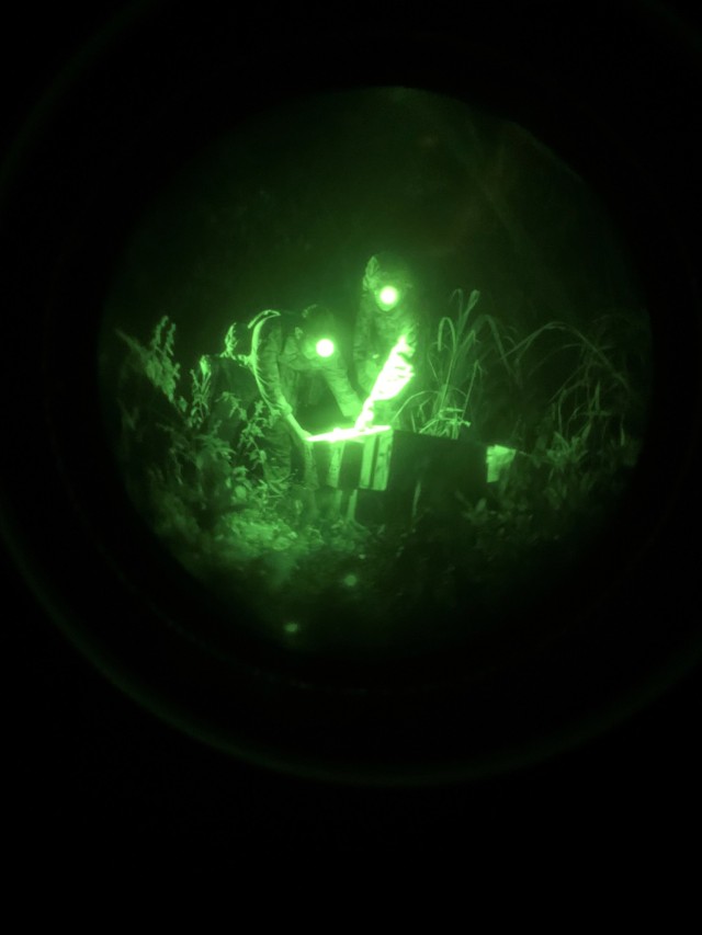 SFC Michael Moore camouflages caches under the cover of darkness in Hawaii’s dense jungle terrain, October 7, 2024, on Pohakuloa Training Area.