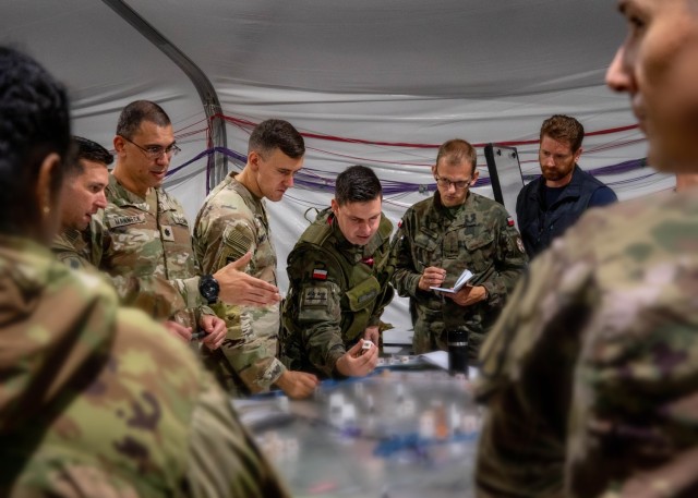 Maj. Ryan Hamilton, a field artillery officer with the 1st Cavalry Division Artillery, discusses with Polish officers over a map during Avenger Triad 24, Sept. 12, 2024, in Boleslawiec, Poland. Avenger Triad 24 is a U.S. Army Europe and Africa...
