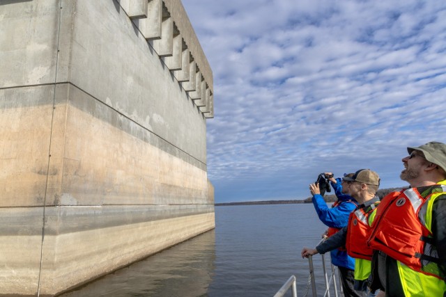 Structural Engineer Sam Leimer (blue jacket), Electrical Engineer Jason Jestila, and Maintenance Engineering Section Chief J.C. Randazzo (bucket hat) inspecting structural, electrical and other instruments on the exterior of the Hilldale Dam...