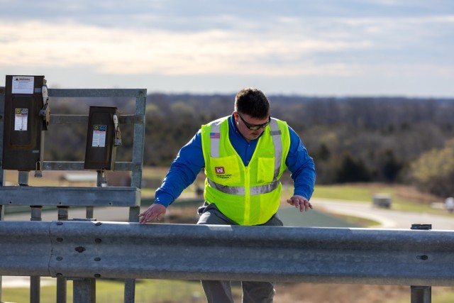 Electrical Engineer Gavin Jones crossing the bridge after inspecting outside electrical systems and its components on the downstream side of the Hilldale Dam and reservoir during the five-year periodic dam inspection.
