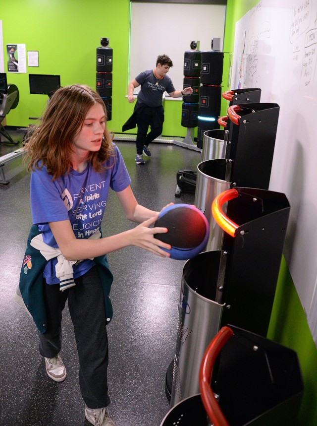 Eighth-grader Rachel Temple transfers a weighted ball to different Heavyball exergaming receptacles as prompted while eighth-grader Cooper Schmitdke hits where indicated on the Fit Interactive 3 Kick exergaming equipment in the Move-to-Learn Lab...