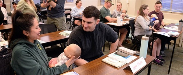 Participants practice holding and repositioning babies during a newborn care class offered by the New Parent Support Program.