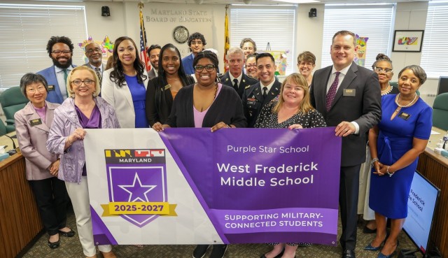 Fort Detrick School Liaison Officer (SLO), Ms. Andrea Bridgewater-McCarthy stands with faculty and staff of West Frederick Middle School at the recent Purple Star Designation program hosted by the Mar