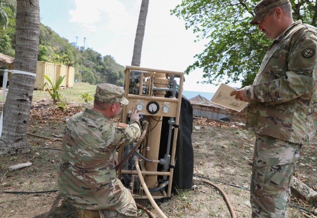 Spc. Colton Hines, left, a water purification specialist with the 935th Aviation Support Battalion, Missouri National Guard, checks the reading on a lightweight water purifier during TRADEWINDS 25 (TW25) exercise at Teteron Bay, Trinidad and...