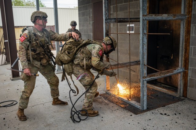 Capt. James Mitchiner with the 75th Ranger Regiment in Fort Benning, Georgia, uses an exothermic torch system to cut metal rods to breach a doorway, while teammate 1st Lt. George Madden stands ready to assist during the 2025 Best Sapper...