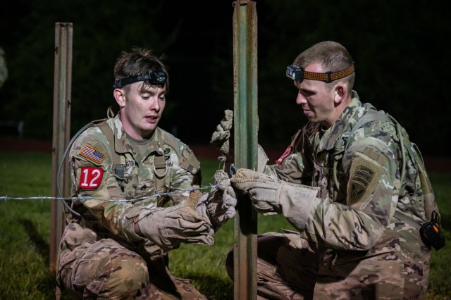 Staff Sgt. Tanner Worthington and 1st Lt. Clayton Hanson, with the 6th Brigade Engineer Battalion, 11th Airborne Division in Fort Richardson, Alaska, work together to tie barbed wire in apron knots during the 2025 Best Sapper Competition April 26...