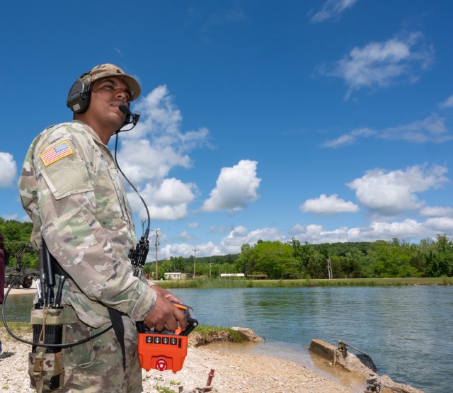 Sgt. Mariano Negron, with the 74th Multi-Role Bridge Company at Fort Cavazos, Texas, concentrates as he turns a bridge erection boat around in the water using a handheld controller May 13 at Fort Leonard Wood’s Training Area 250 lake.