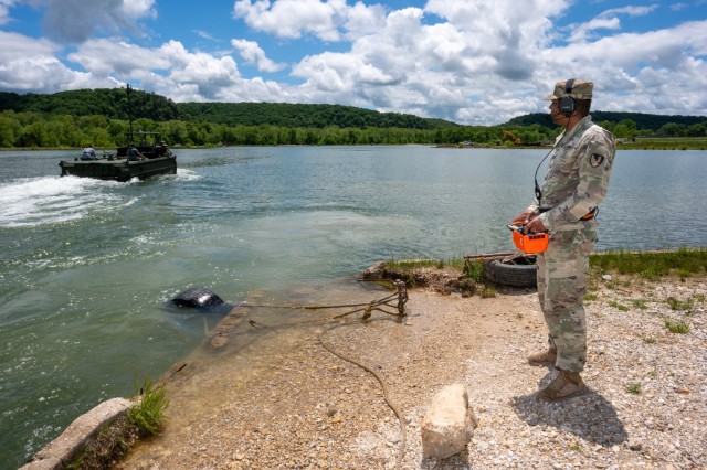 Sgt. Mariano Negron, a bridge crewmember with the 74th Multi-Role Bridge Company at Fort Cavazos, Texas, controls a bridge erection boat, commonly called a BEB, from a handheld controller May 13 at Fort Leonard Wood’s Training Area 250 lake.