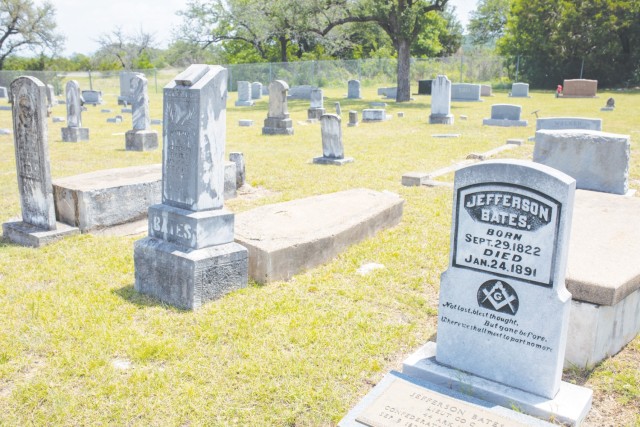 Rows of headstones sit in a grassy field.