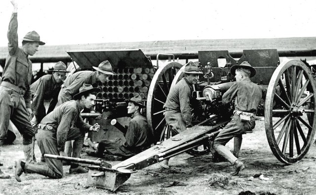 a black and white photo - soldiers load ammunition during artillery training