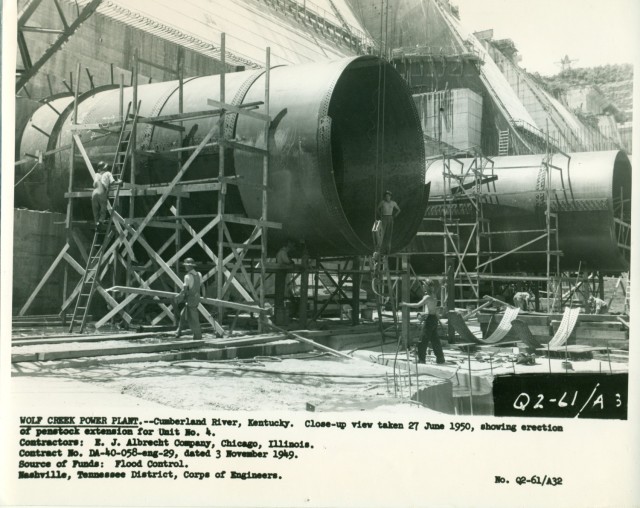 Crews erect the penstock extensions for the Wolf Creek Dam Powerhouse June 27, 1950, on the Cumberland River in Jamestown, Kentucky.  The multi-purpose dam would serve to replace the old locks and dams on the Cumberland River. (USACE Photo)