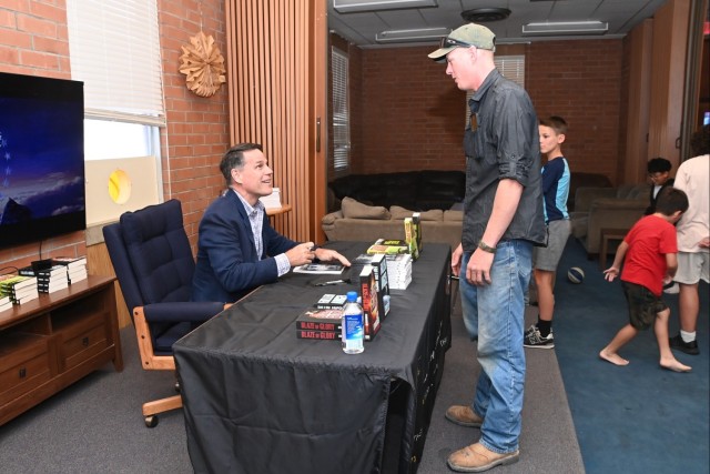 Army Ranger Hall of Fame inductee Jeff Struecker (left) signs books for attendees in the Fellowship Hall of U.S. Army Yuma Proving Ground&#39;s Halo Chapel on June 4, 2025.