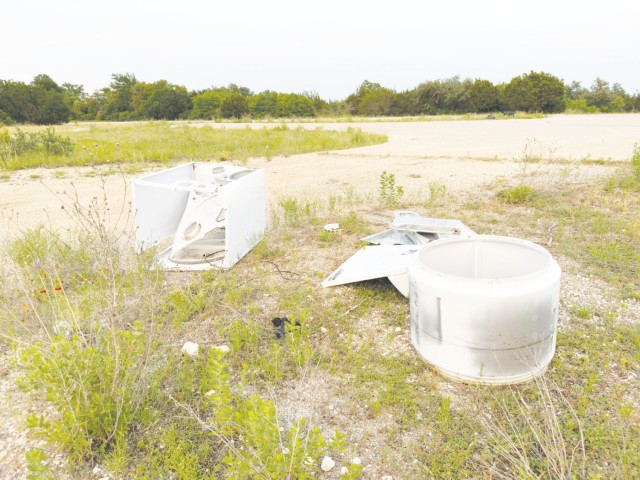 A disassembled washing machine sits on the ground, dirty and bent.