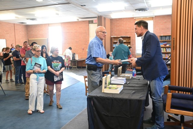 Army Ranger Hall of Fame inductee Jeff Struecker (right) signs books for attendees in the Fellowship Hall of U.S. Army Yuma Proving Ground&#39;s Halo Chapel on June 4, 2025.
