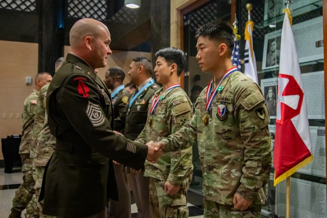 Eighth Army Headquarters and Headquarters Battalion Command Sgt. Maj. John A. Watkins congratulates Cpl. Woo Hyung Lee, during an induction ceremony at Eighth Army Headquarters, USAG Humphreys, South Korea, Oct. 22, 2024. The club recognizes...