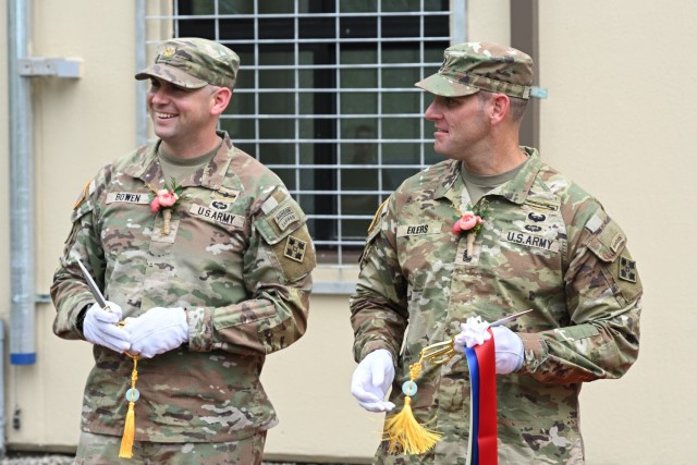U.S. Army Command Sgt. Maj. Michael Eilers, 1-4 Stryker Brigade Combat Team senior enlisted advisor, cuts a ribbon at the newly re-opened Rotational Stryker Brigade Headquarters alongside an officer in his unit, Camp Hovey, June 16, 2025. The...