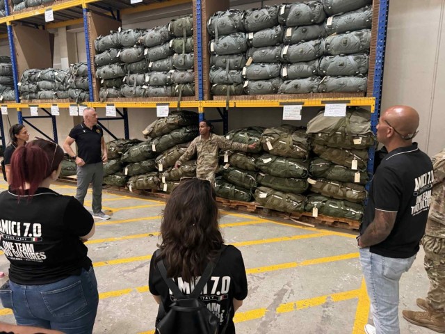 AVIANO AIR BASE, Italy – A Kilo Company, Brigade Support Battalion, 173rd Airborne Brigade rigger explains parachute packing and inspection procedures to AMICI participants inside the Parachute Activity Headquarters.