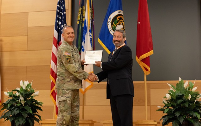 Mike Trzeciak, outgoing PM PNT project manager, accepts an award from Brig. Gen. Ed Barker, PEO, during a change of charter ceremony on APG.