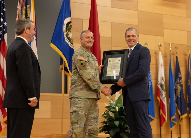 Chris Jais, incoming PM PNT project manager, accepts the organizations charter from Brig. Gen. Ed Barker, PEO, during a change of charter ceremony on APG.