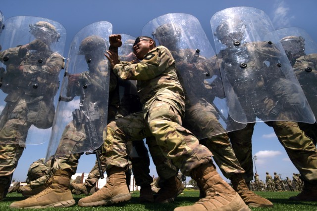 Sgt. 1st Class Andres Agag, a mortar team leader with Troop A, 1st Squadron, 18th Cavalry Regiment, California Army National Guard, pushes against the shields of other unit members while playing the role of an aggressive demonstrator during...