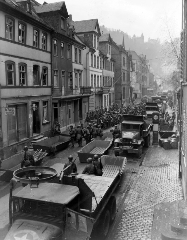 Troops, vehicles, assault boats, and other equipment fill the streets of St. Goar, Germany, as the 89th Division prepares to cross the Rhine on 26 March 1945.
