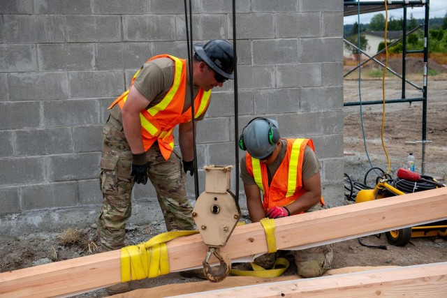 U.S. Army Staff Sgt. Zachary Williamson, left, and Spc. Pharez Telona, with the 176th Engineer Company, 420th Chemical Battalion, 96th Troop Command, Washington National Guard, prepares the beam for installation on the roof of a restroom facility...