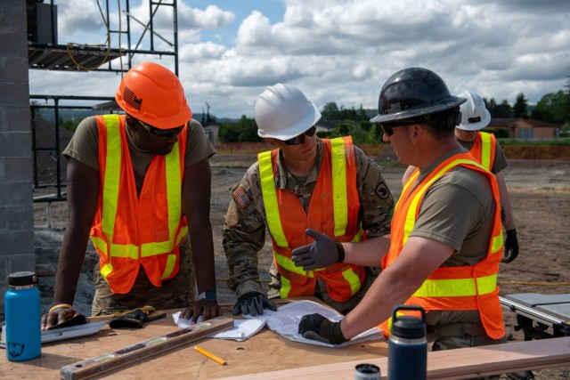 U.S. Army Staff Sgt. Zachary Williamson, right, with the 176th Engineer Company, 420th Chemical Battalion, 96th Troop Command, Washington National Guard, is instructing Soldiers in his unit about tongue and groove roof decking for the restroom...