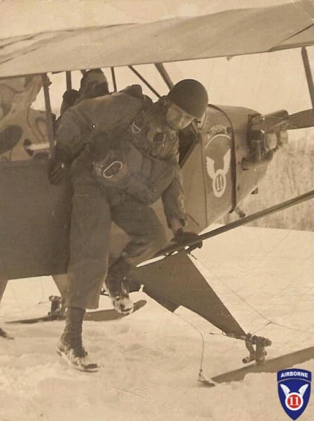 A paratrooper from the 11th Airborne Division dismounts a J-3 Piper Cub specially fitted with skis during cold weather training.