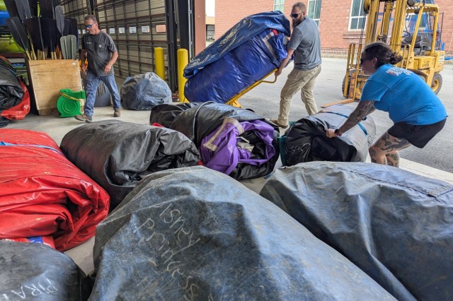 Brandon Reynolds, Greg Connell and Jessica Guyton move inflatables out of the storage area and onto a flatbed truck in preparation to move items from the Outdoor Recreation facility to Division Hill for Mountainfest. Some of their inventory was...