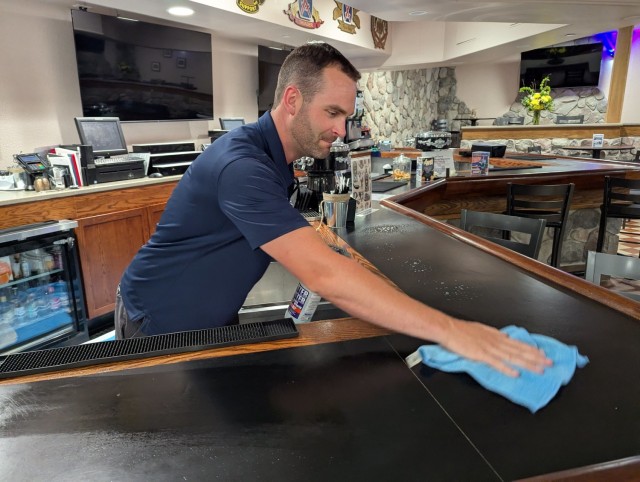 Charlie Rhode, Fort Drum FMWR Business and Community Recreation Division deputy chief, cleans off the bar counter in preparation for the evening social for Gold Star families in The Ridge. (Photo by Mike Strasser, Fort Drum Garrison Public Affairs)