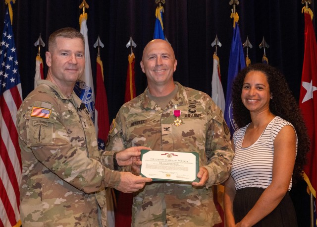 PICATINNY ARSENAL, N.J - Maj. Gen. John T. Reim (left) presents the Legion of Merit to Col. Joshua Headley (center) who is joined by his wife Patrice (right) during a change of management ceremony at Picatinny Arsenal.