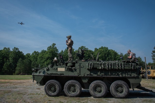 A contractor stands atop of a Stryker tracking the movement of a drone during a testing event.