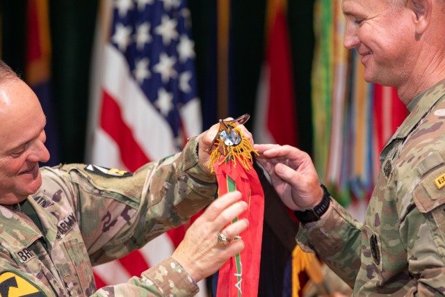 Lt. Gen. Miles Brown, Army Futures Command deputy commanding general, left, and Maj. Gen. John Cushing, U.S. Army Combat Capabilities Development Command, or DEVCOM, commanding general, affix the Army Superior Unit Award streamer to the DEVCOM...