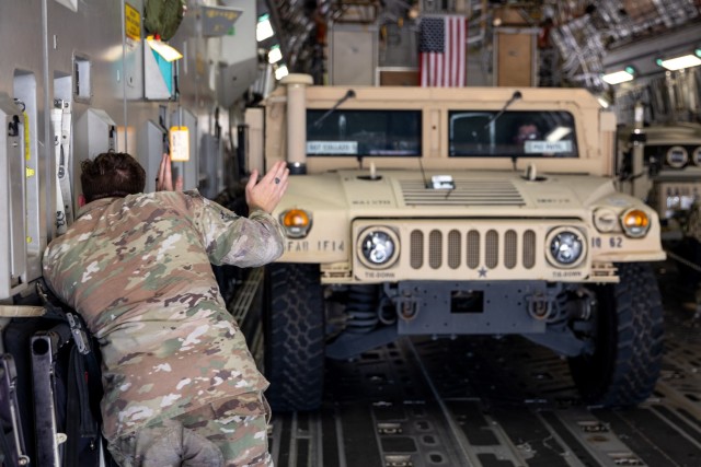 A Soldier assigned to the 1st Battalion, 14th Field Artillery Regiment (1-14th FAR) guides a driver to load a HMMWV onto a C-17 as part of Strategic Airlift (STRATAIR) operations at the Lawton Regional Airport June 30, 2025. 1-14th FAR deployed to...