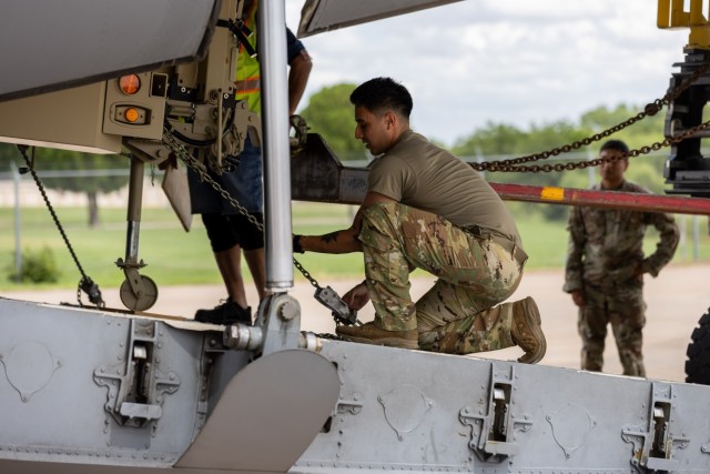 A Soldier assigned to the 1st Battalion, 14th Field Artillery Regiment (1-14th FAR) secures a trailer to a C-17 as part of Strategic Airlift (STRATAIR) operations at the Lawton Regional Airport June 30, 2025. 1-14th FAR deployed to Europe in...