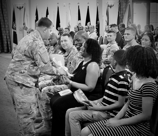 Mrs. Lyles, spouse of Command Sgt. Maj. DeMarius M. Lyles, receives a bouquet of yellow roses as a welcome gift for her and her family during her husband&#39;s  Assumption of Responsibility ceremony 10 July, 2025 held at the Sandy Basic Community...