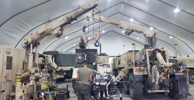 Soldiers from Cannon Field Maintenance Team and F Forward Support Company perform services on an M1068 Standard Integrated Command Post System using the crane from a maintenance platoon wrecker in a maintenance bay at Forward Operation Site Torun,...