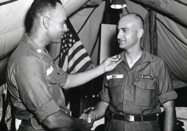 Then-LTC Arthur Gregg, commander of the 96th Supply & Service Battalion, conducts a promotion ceremony for CPT Sandy Hertz while deployed to Cam Rahn Bay, Republic of Vietnam, circa 1967.