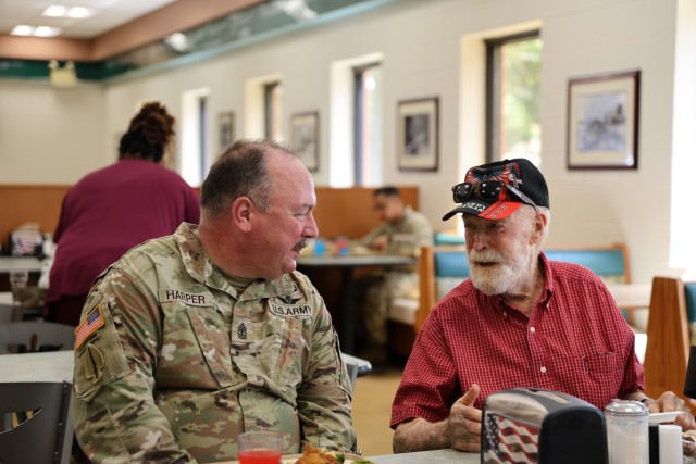 1SG Harper talks with a veteran from the Command Sgt Maj Bennie G. Adkins State Veterans Home during the Legacy Lunch event held at the Dining Facility on Fort Rucker.