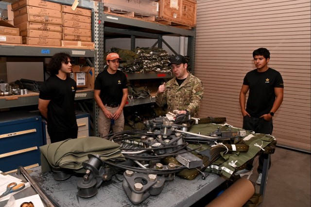 Staff Sgt. Kyle Dunwiddie (second from right) gives recent Army recruits a tour of U.S. Army Yuma Proving Ground&#39;s Air Delivery facility on July 10, 2025. “It’s definitely fun getting to interact with the local population, especially kids...