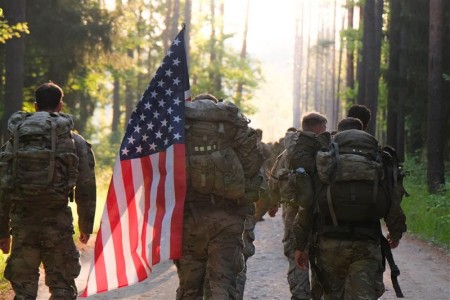 Soldiers walking, one carrying American flag