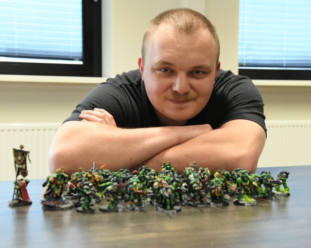 Edward Lopez sits behind a row of miniature war game figures on a table