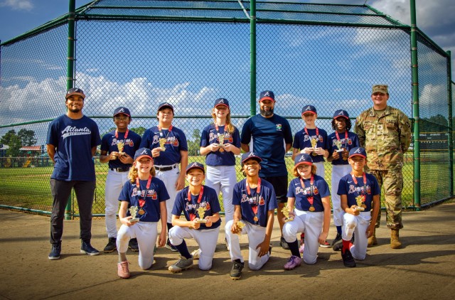 Players and coaches with the Fort Gordon Braves youth baseball team pose for a post-season photo at Fort Gordon, Georgia, July 22. Ten of the team’s 13 players are pictured following their fourth consecutive YMCA league title.