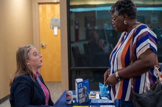 Amber Martinez, assistant director of admissions at Athens State University, discusses the admissions process with Amanda Peart, a military spouse, at the mini college fair hosted by the Education Center on July 23.