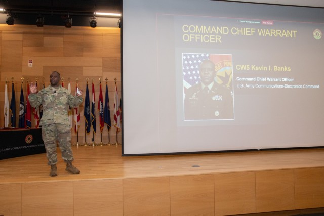 CECOM Command Warrant Officer 5 Kevin I. Banks introduces himself and debuts Episode 1 of 'Snacks with Saacks' video series during the summer CECOM Town Hall at Myer Auditorium on July 29, 2025.
