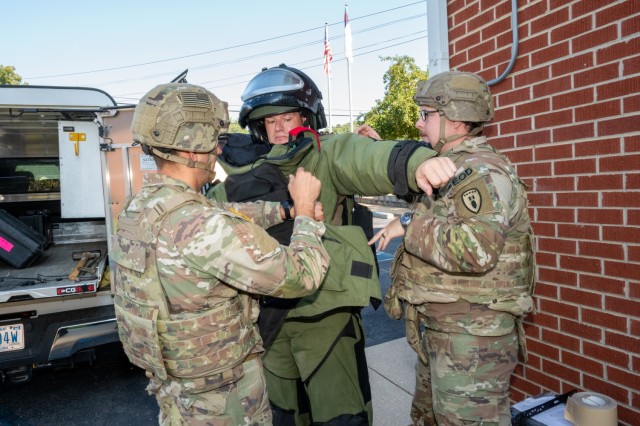 Soldiers from the 763rd Ordnance Company (EOD), Sgt. Craig Qualley (left) and Spc. Edwardo Hall (right), help Staff Sgt. Joshua Luebke put on a bomb suit to prepare him to enter a community center Aug. 5 in Waynesville, Missouri, during a homeland...