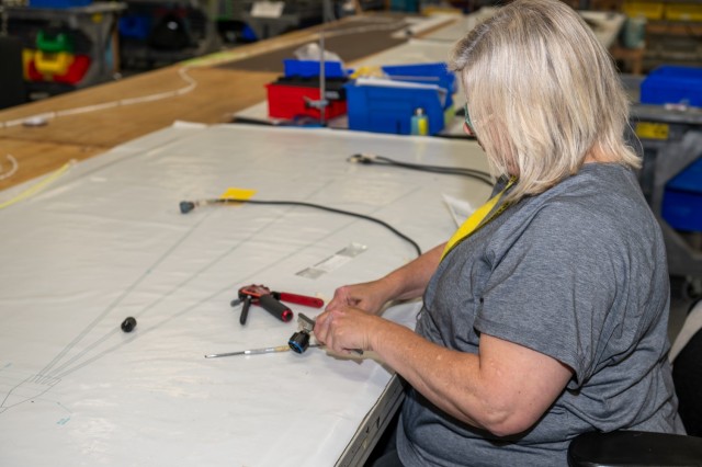 Terra Legg, electronics mechanic at Tobyhanna Army Depot (TYAD), performs step one of the cable prepping and potting process by cleaning solder splash off the cables. Power cables are a critical component to the HMS radio integration A-kits,...