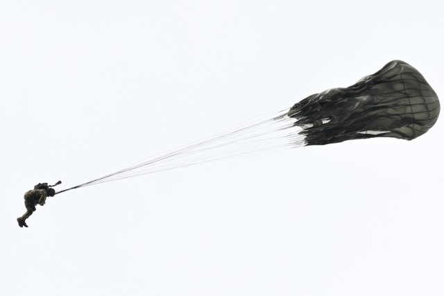 A Spartan paratrooper from the 2nd Infantry Brigade Combat Team (Airborne), 11th Airborne Division puts his “knees in the breeze” over Malemute Drop Zone at Joint Base Elmendorf-Richardson as part of the celebration of National Airborne Day,...