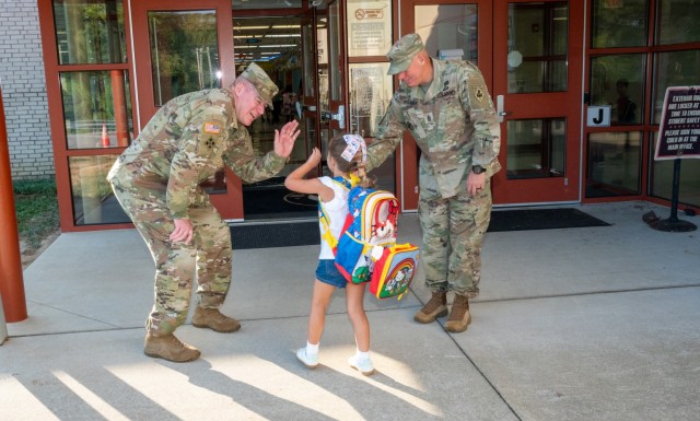 Maj. Gen. Christopher Beck, Fort Leonard Wood and Maneuver Support Center of Excellence commanding general (left), and U.S. Army Engineer School Command Sgt. Maj. David Palmer (right), greet a student arriving at East Elementary Aug. 18, the first...