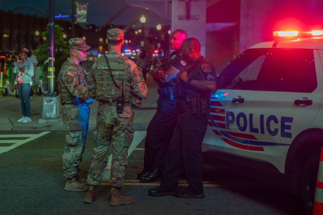 Army 2nd Lt. Harry Siegel and Sgt. 1st Class Nikolay Bashko, both assigned to Joint Task Force District of Columbia as part of the D.C. Safe and Beautiful Task Force, talk with Metropolitan Police Department officers near Nationals Park in...